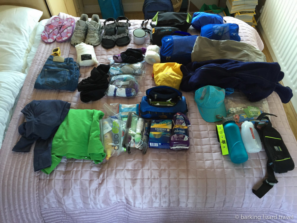photo of clothes and other items layed out on a bed for packing