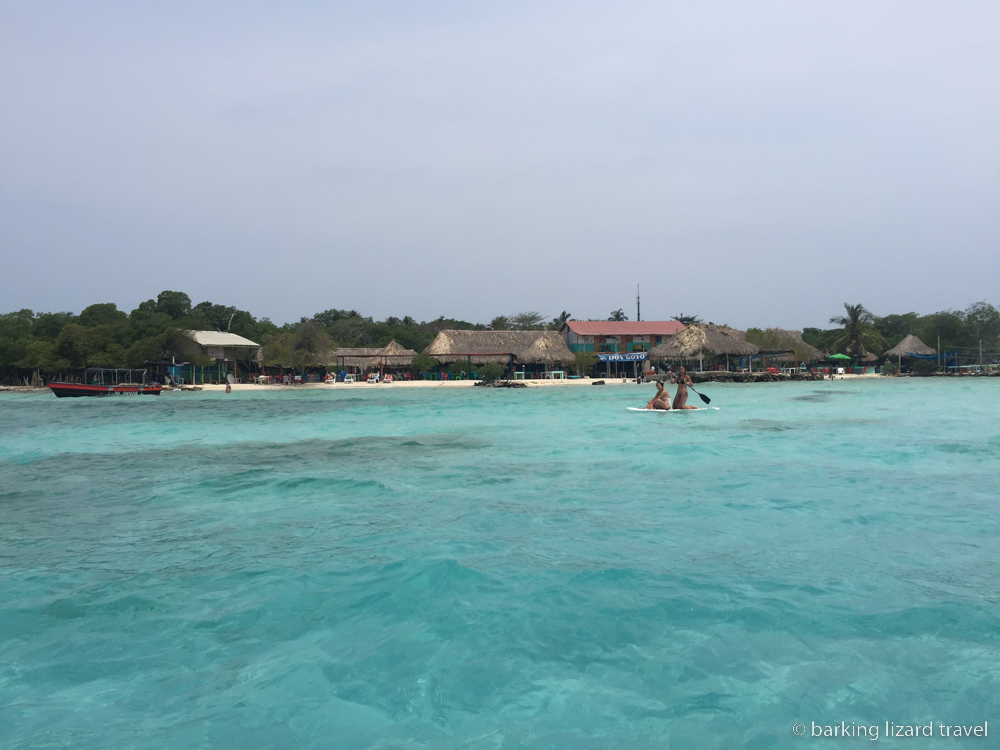 photo of the turquoise sea with two women paddle boarding in the back in the sea off the coast of Isla Mucura