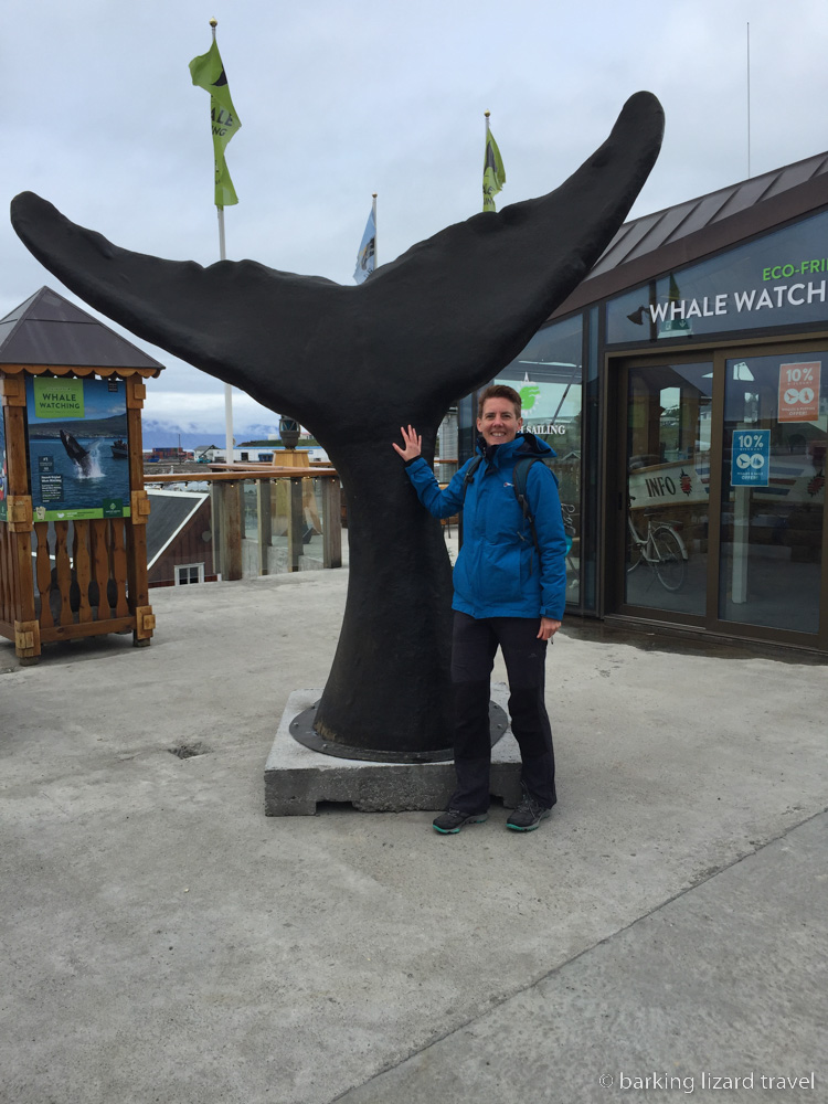 photo of author standing by a sculpture of a whales tail fin