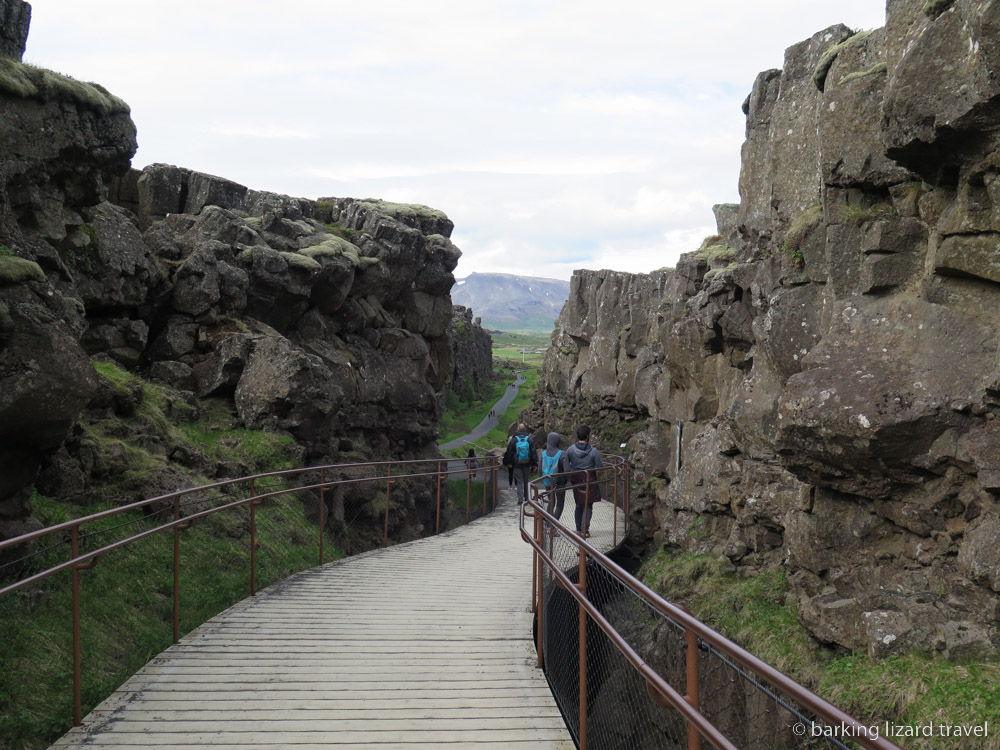 two people walk between the rocks at Thingveller National Park 
